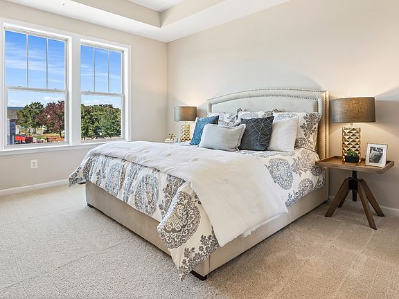 Carpeted owner s suite with large double window at a DRB Homes Upton II Model at the Canterbury Stat