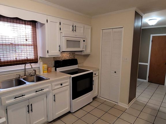 Double sink, dishwasher, glass top stove with self cleaning oven, microwave, and pantry. Room flows off the foyer and into the living room. Door access to the carport as well.