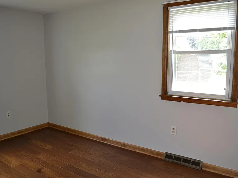 Bedroom 1. Two windows, hardwood floors, closet.