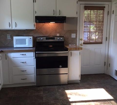 Kitchen includes microwave and range, with side door to deck and second door to lower level.