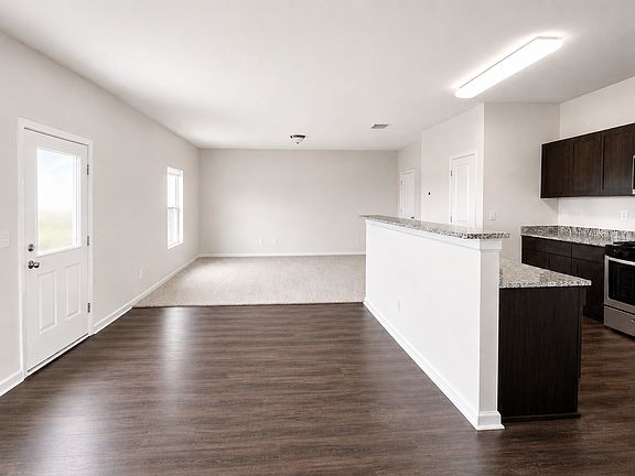 Kitchen with dark wood flooring, range, light stone countertops, and appliances with stainless steel finishes