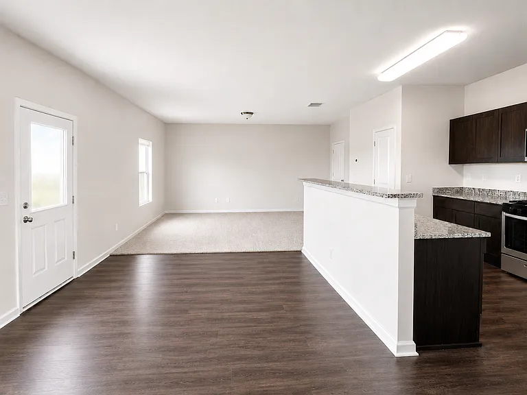 Kitchen with dark wood flooring, range, light stone countertops, and appliances with stainless steel finishes