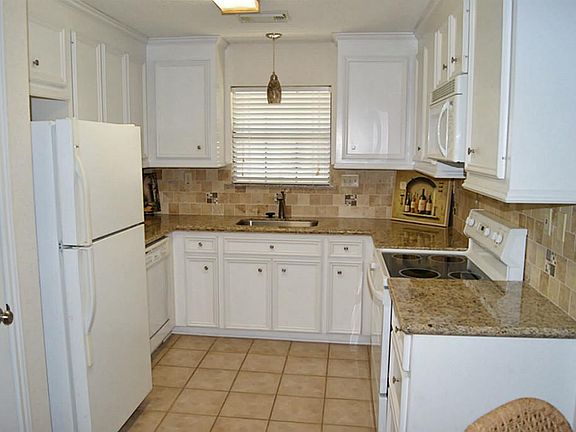 KITCHEN WITH GRANITE COUNTER TOPS AND TILE BACKSPLASH