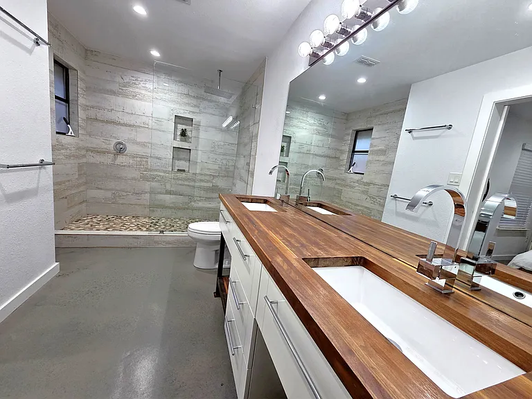 Dual Vanity Master Bathroom has large rain shower designed with barn tiles and river rock floor