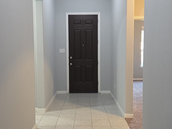 Corridor featuring arched walkways, tile patterned floors, and a raised ceiling