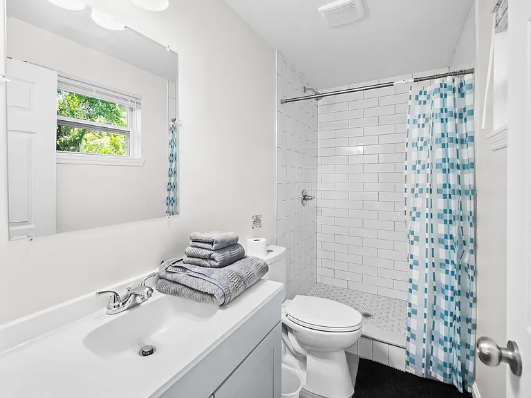Updated bathroom with a subway-tile shower, ample vanity counter space, and a window for natural light and ventilation.