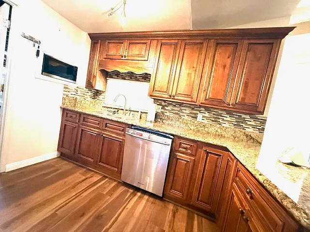 The kitchen is equipped with a wall-mounted microwave, built-in dishwasher, refrigerator, cooktop, and oven_designed for both functionality and convenience.