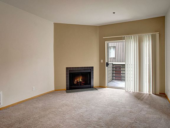 Living room with wall to wall carpeting and large sliding glass doors leading out to the private balcony and fireplace