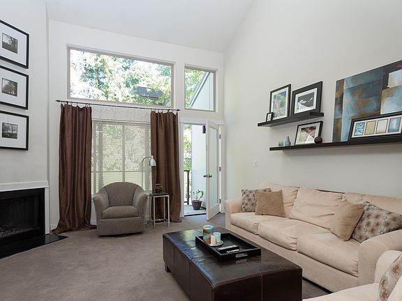 Vaulted ceilings and a wood burning fireplace in living room that opens up to a deck with storage.