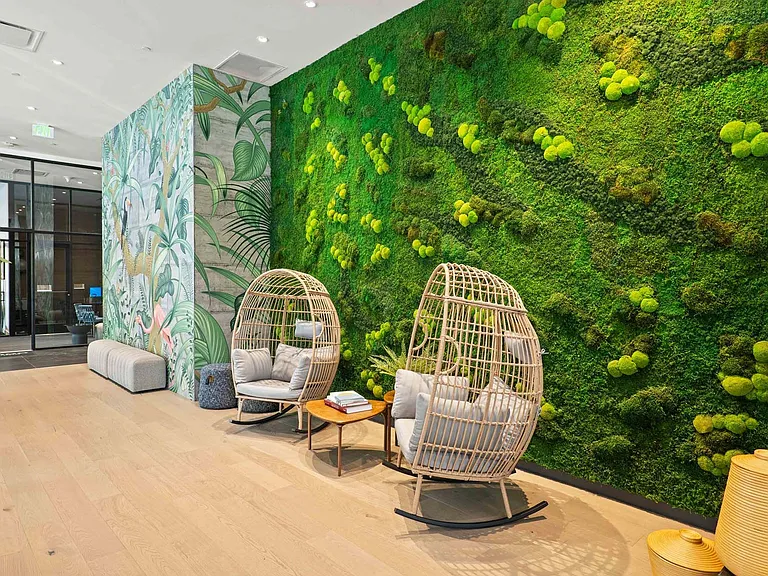 Enter a stylish space with a mossy green wall and two egg rocking chairs, perfect for a cozy atmosphere.