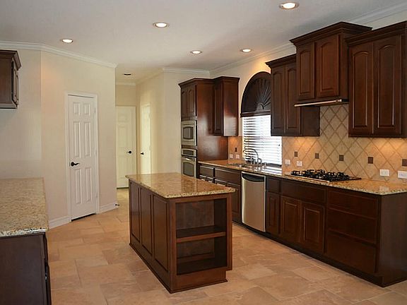 Island kitchen features upgraded granite, gas cooking,  walk-in pantry and stainless appliances.