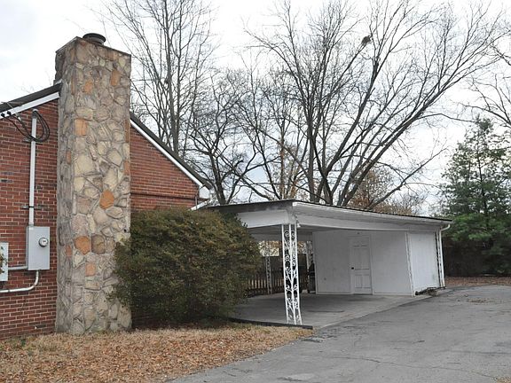 Side view of the House with a Two-car Carport, Storage, and an Additional Parking Spot Behind the Storage.