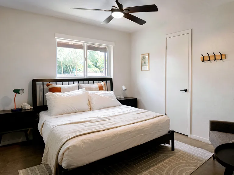 Peaceful queen bedroom with garden window views and warm desert accents.