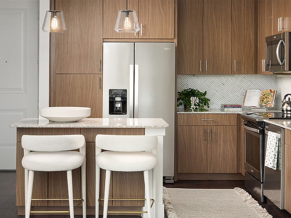 Apartment kitchen with stainless steel appliances, granite countertops, and wood-style flooring.