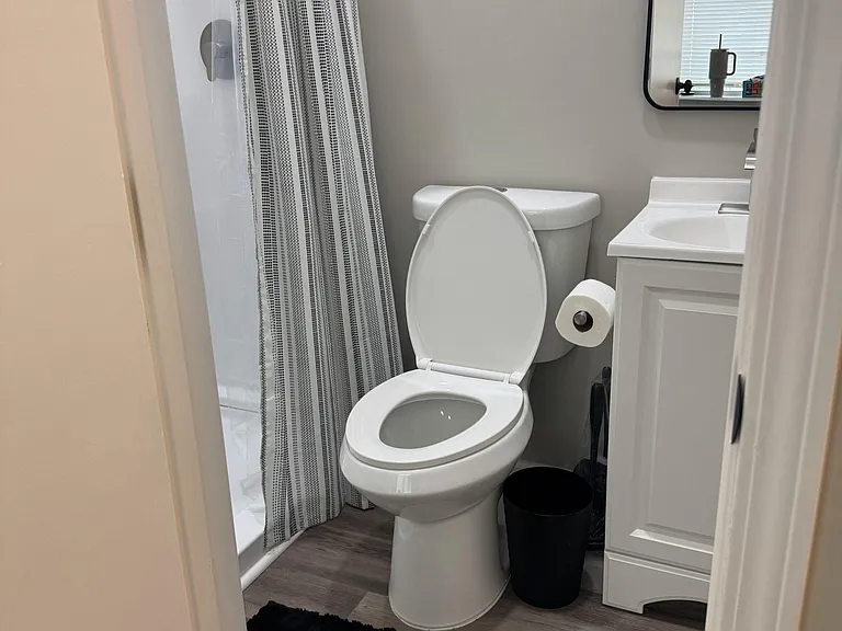 Full bathroom with a shower combo, vanity sink with mirror, and durable flooring for easy upkeep.