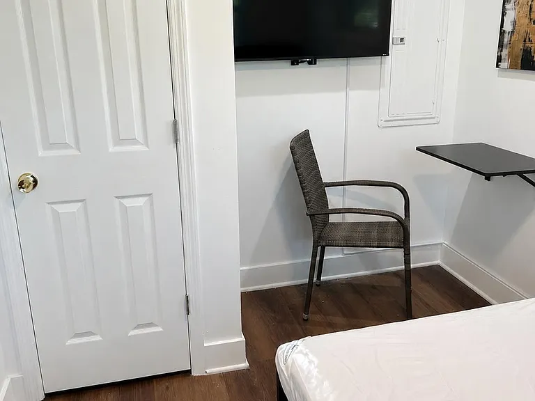 Efficient bedroom with wood-look floors, wall-mounted TV, and a compact work surface for studying or remote work.
