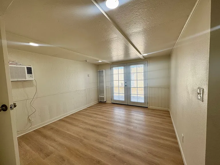 French Doors allow the living room to be flooded with light. There are attached blinds on the doors for privacy. A/C and heater wall unit.
