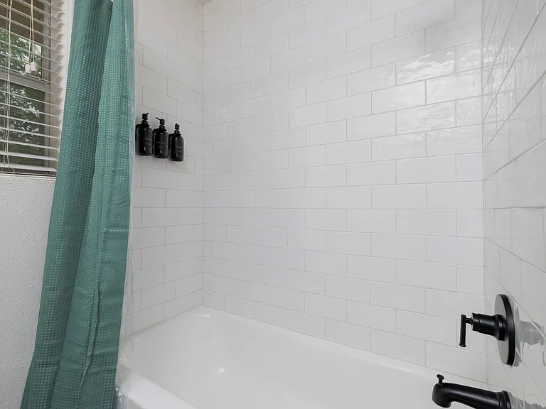 Full bathroom with double sinks and shower-tub combo attached to bedroom 1.
