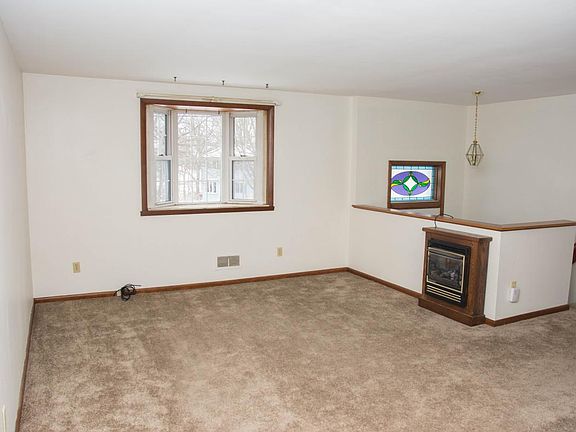 Spacious living room has working gas fireplace, view of stained glass transom in entryway above front door