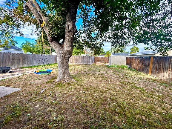 Backyard has a huge tree to keep things shaded, an area for gardening, a metal shed, and gated parking in the backyard alley.