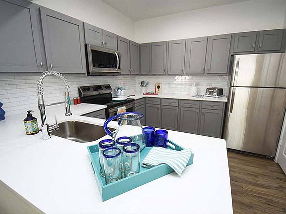 Kitchens feature stainless steel appliances and gray or white shaker-style cabinets and countertops