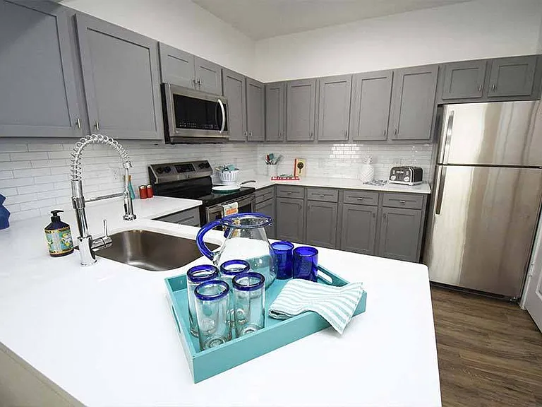 Kitchens feature stainless steel appliances and gray or white shaker-style cabinets and countertops