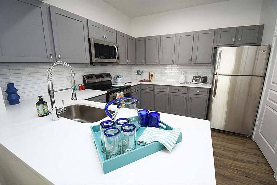 Kitchens feature stainless steel appliances and gray or white shaker-style cabinets and countertops