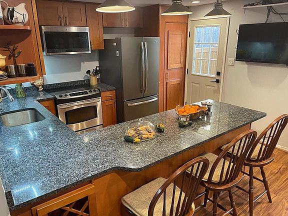 Kitchen, located just beyond the living room. Door is to the backyard. TV mounted on wall can stay if you prefer.
