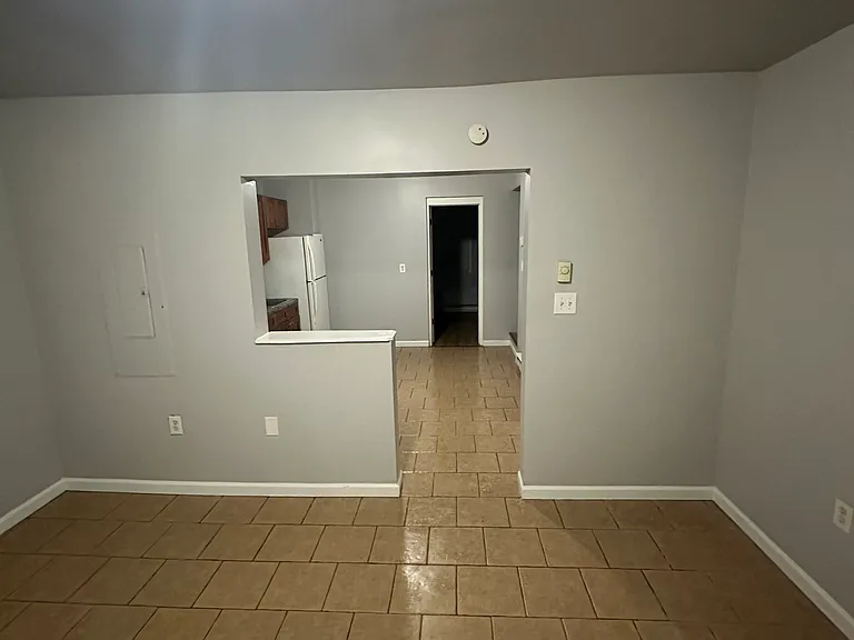 Living room through kitchen, leading into first bedroom view