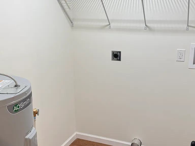 Private laundry room with washer and dryer to be installed before move-in, convenient in-unit laundry hookups, additional shelving for storage, and durable flooring.
