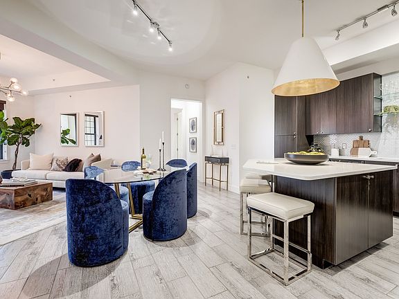 Open living room and kitchen concept with dining area, natural lighting and wood-like finish tile flooring