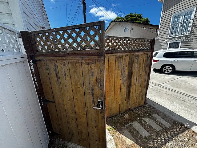 Entrance to Cottage & private area. Fence to be painted white soon! Our building in photo with the white car, has a gated entrance to the yard and coin op laundry room.