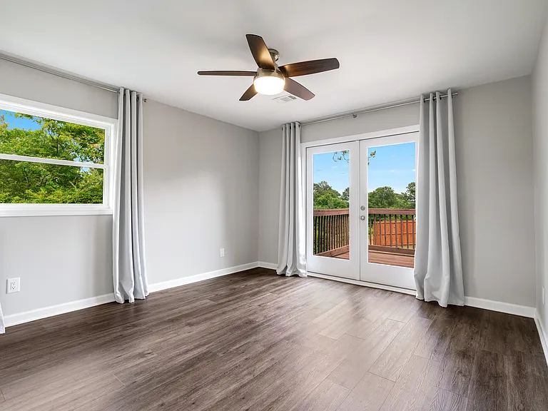 Bright second bedroom with charming double French doors opening onto a private outdoor deck.