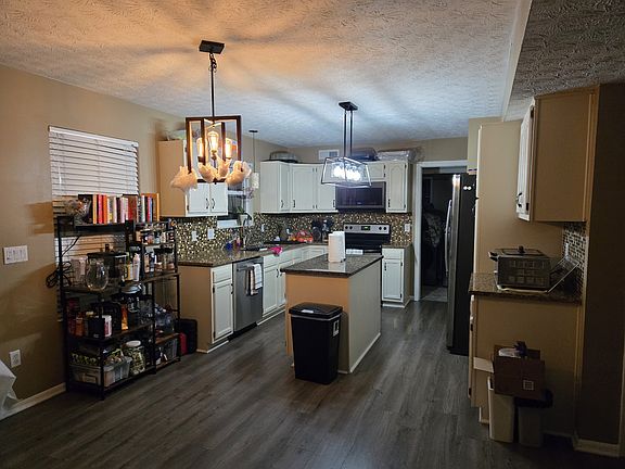 Downstair kitchen w/ tenant fridge (landlord has her own fridge); Outdated photo - new trash can and two black cocktail tables under the warm light