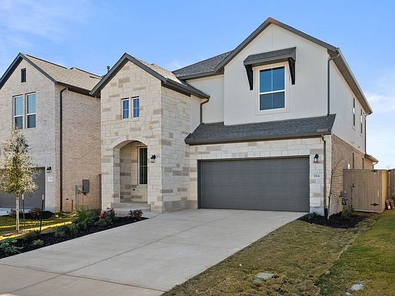 A two-story residential house with a garage, surrounded by a well-manicured lawn and landscaping, se
