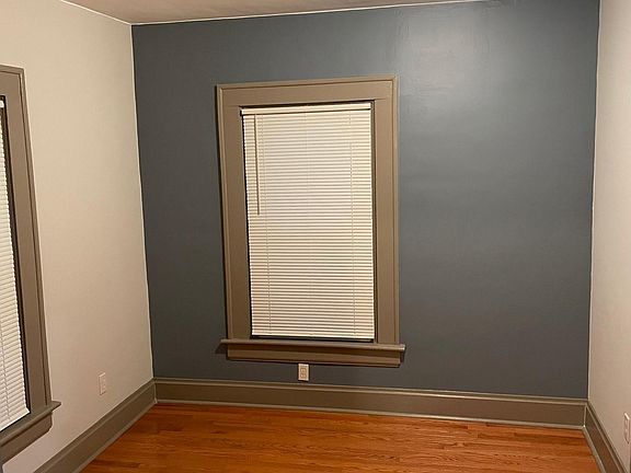 First Bedroom - gorgeous new hardwood flooring. Blue accent wall, Miniblinds. Room measures approx. 10x11 feet.