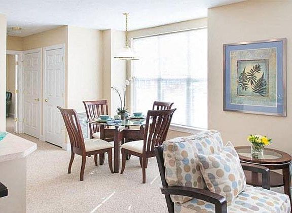 View from near kitchen breakfast bar of great room living and dining areas and hallway to bedroom