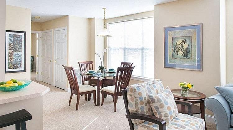 View from near kitchen breakfast bar of great room living and dining areas and hallway to bedroom