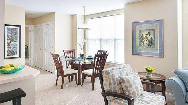 View from near kitchen breakfast bar of great room living and dining areas and hallway to bedroom
