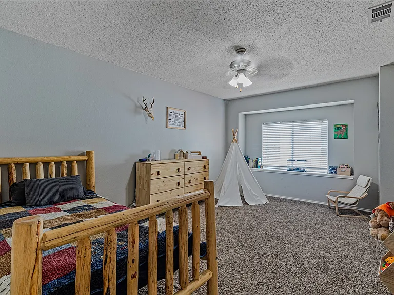 Spacious room featuring light gray walls and textured carpeting