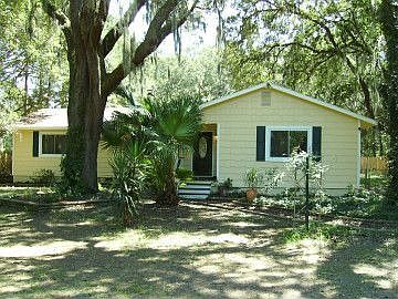 Front of house with huge live oaks.