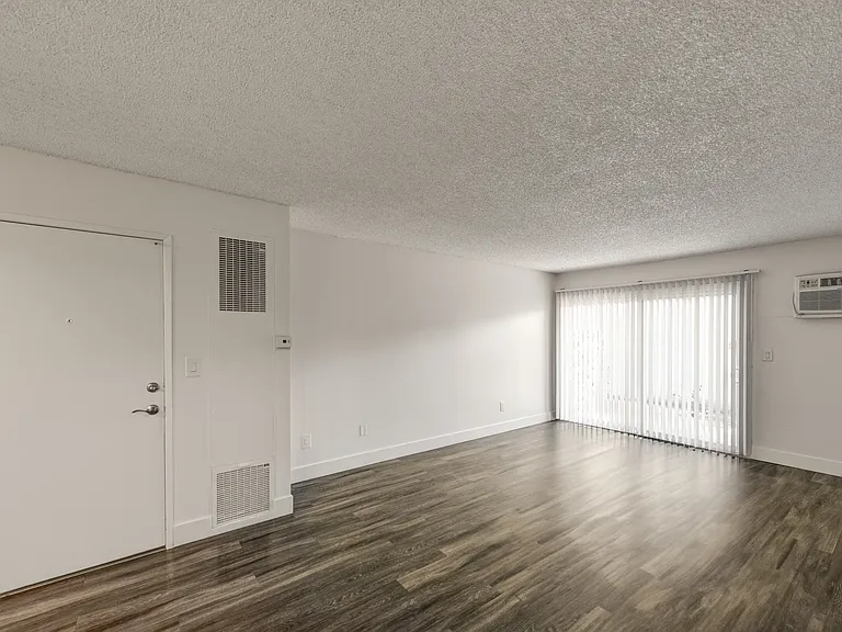 an empty living room with wood flooring and a window