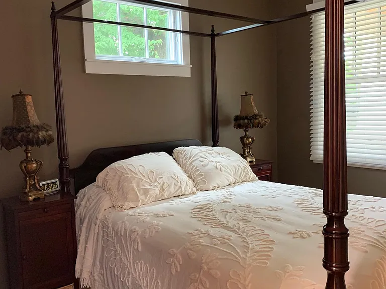 Canopy bed with a chenille bedspread.