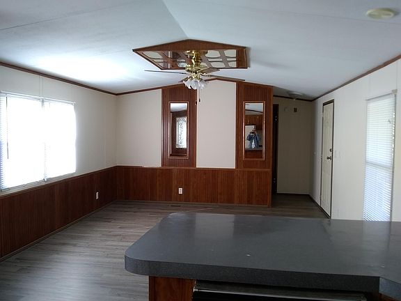 Living Room from Kitchen showing front door and hallway to smaller bedroom and full bath with shower tub