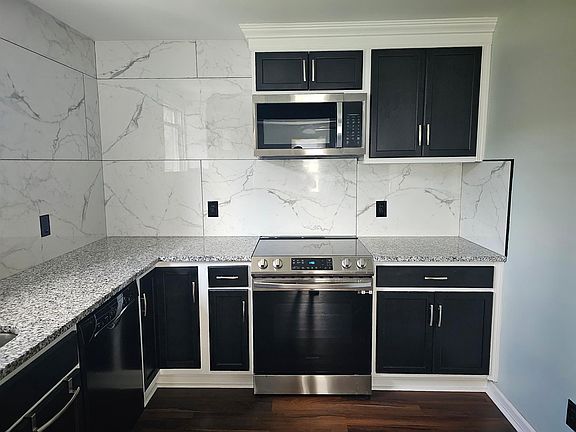 Custom Black Cabinets with Crown Molding. Stainless Steel Electric Stove. Stainless Steel Microwave with exhaust vent.