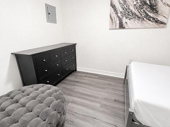 Private bedroom with wood-style flooring, a ceiling fan, and a dresser for convenient storage.