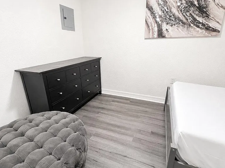 Private bedroom with wood-style flooring, a ceiling fan, and a dresser for convenient storage.