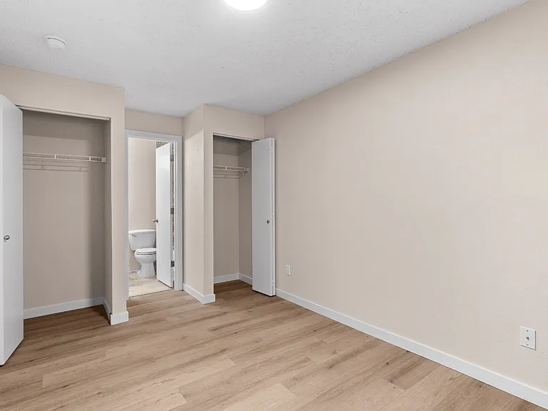 A comfortable bedroom with two closets, durable wood-style flooring, and convenient access to the bathroom. A comfortable bedroom with two closets, durable wood-style flooring, and convenient access to the bathroom.