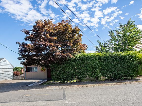 The tall wall hedge provides the front yard with privacy and a lush green look. Cherry and Maple trees provide extra shade.>