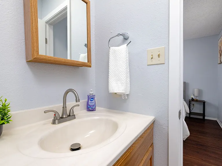 Ensuite-style bathroom with a functional vanity and mirror, steps from the bed.